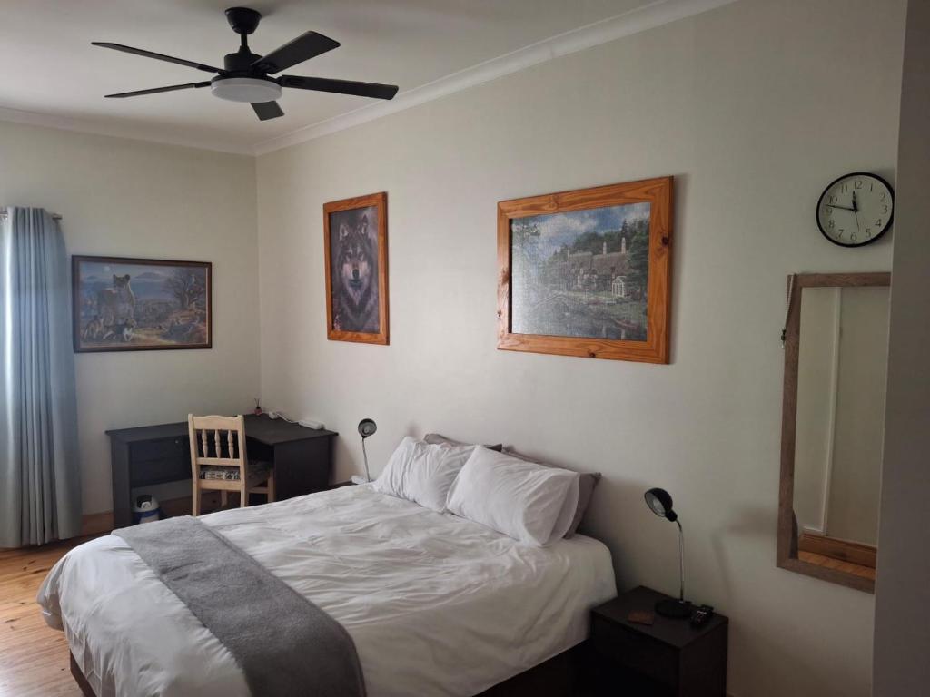 a bedroom with a bed and a clock on the wall at R & A's Cottage in Strand