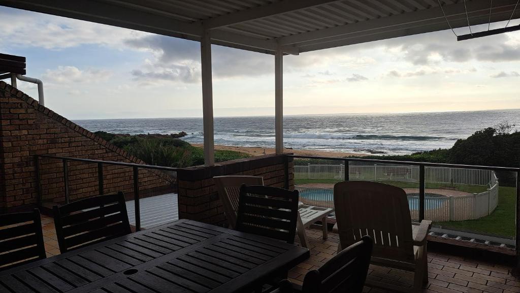 a balcony with a table and chairs and the ocean at Hibberdene Beachfront Self-Catering 9 Catalina Bay in Hibberdene