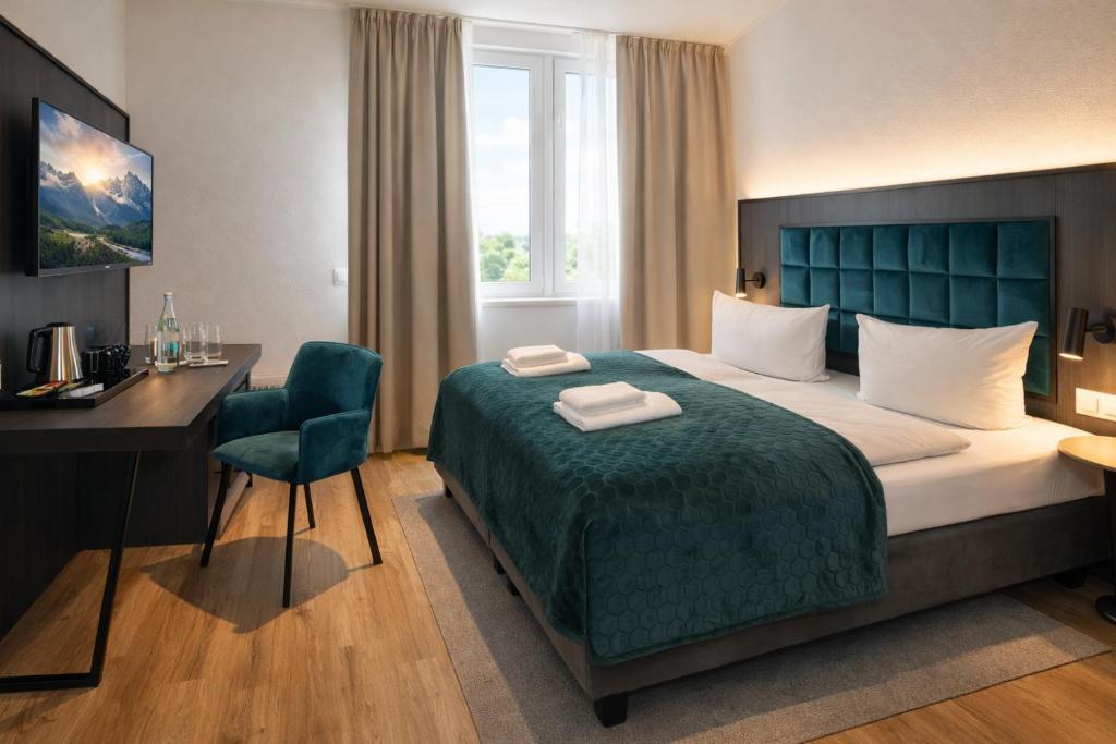 a hotel room with a bed and a desk and a desk at Hotel Hamburg Nord in Norderstedt