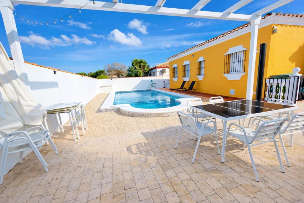 a patio with a table and chairs next to a pool at Casa oasis de chiclana in Novo Sancti Petri