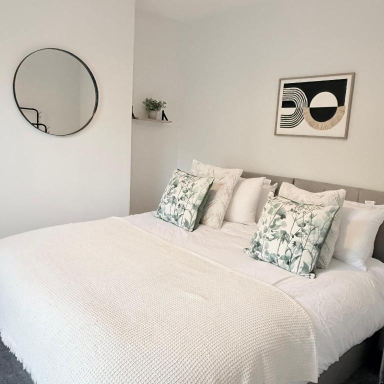 a bedroom with a white bed with pillows and a mirror at 171 Stroud Road in Gloucestershire