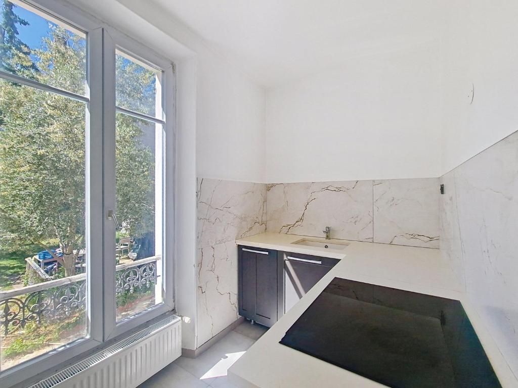 a kitchen with a counter and two large windows at Bel Appart 10 min de Paris et Orly in Juvisy-sur-Orge