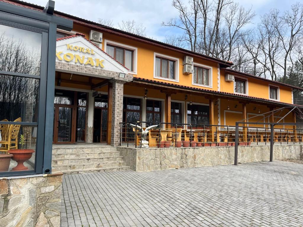 a building with tables and chairs in front of it at Kompleks Koral Konak in Prezhda