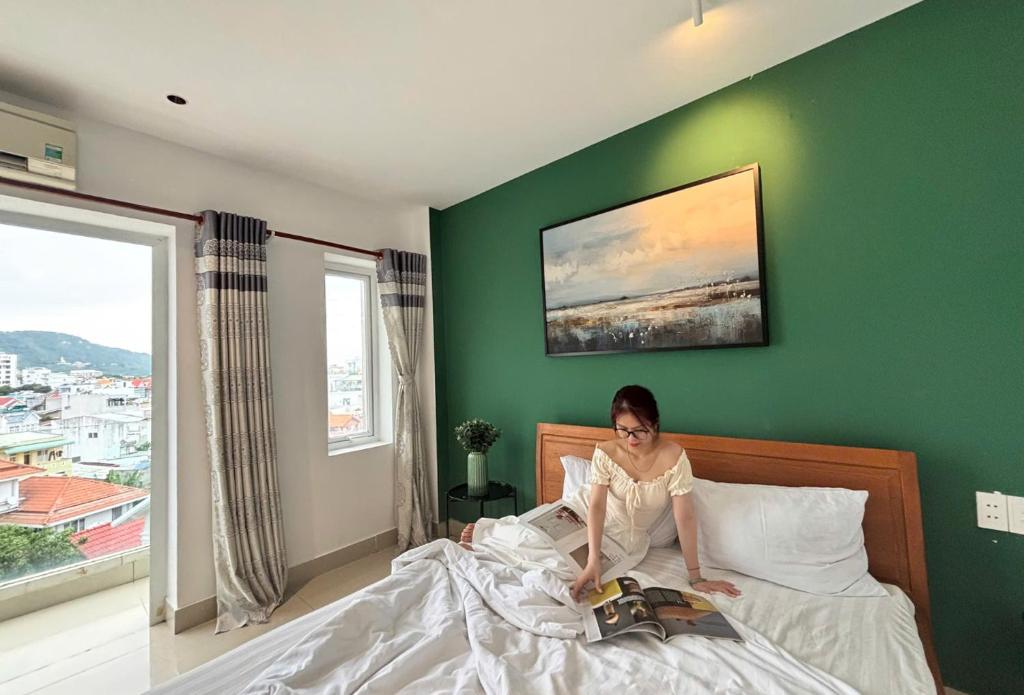 a woman sitting on top of a bed at Joi Hospitality - Anthony in Vung Tau