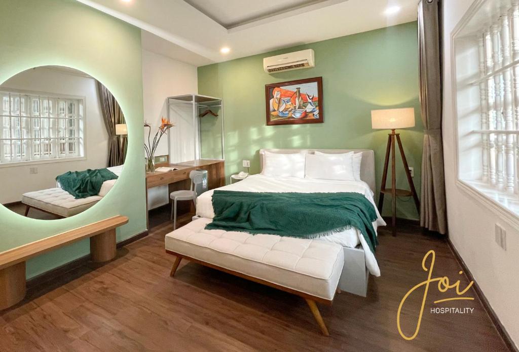 a bedroom with a bed with a green wall at Joi Hospitality - Central in Vung Tau