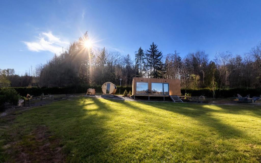 a large grassy field with a house in the middle at ermiglamping in Jince