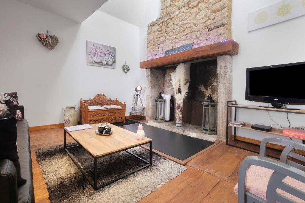 a living room with a fireplace and a tv at La Perle Rosée in Azerat