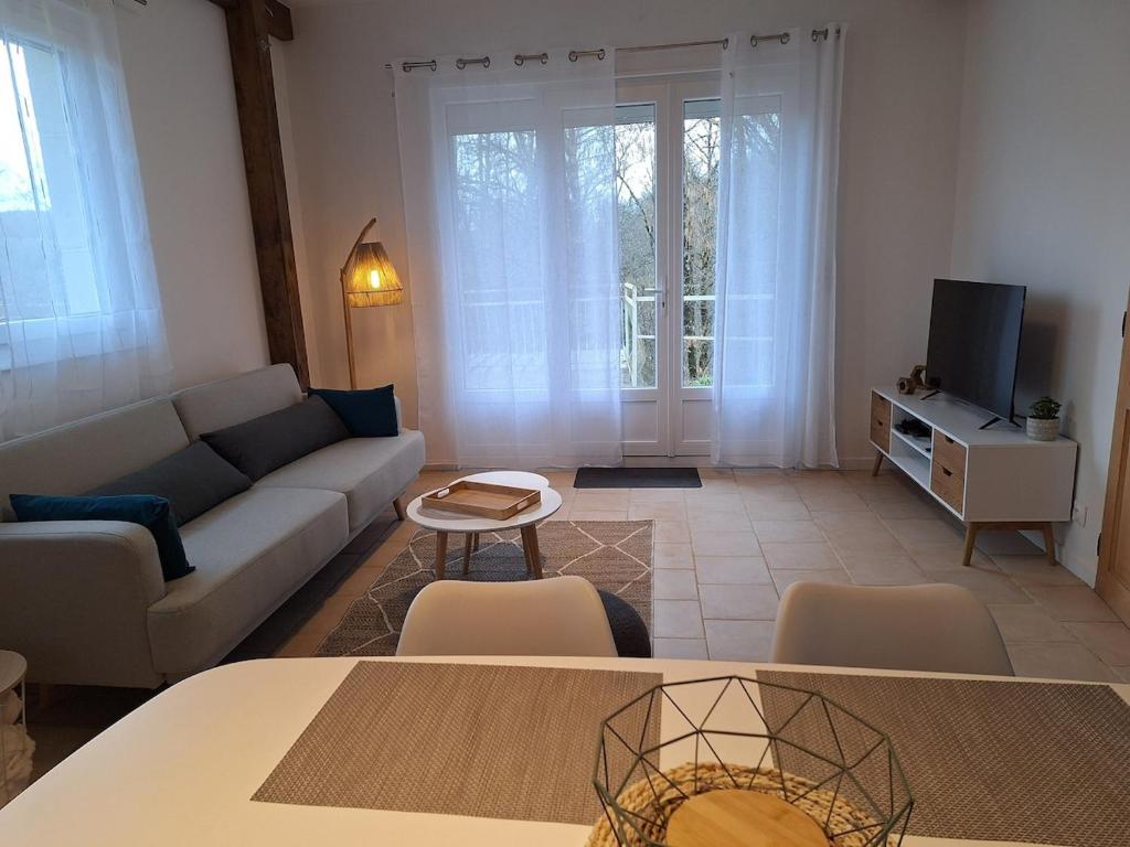 a living room with a couch and a tv at Escapade au Lac in Corancy