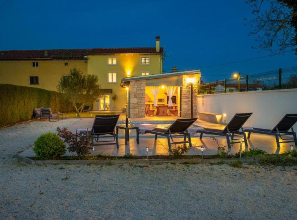 a group of chairs sitting on a patio at night at Villa Prestige Azinetti with Pool in Štokovci