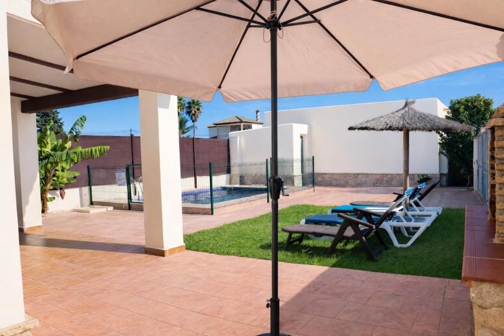 a patio with an umbrella and a table and chairs at Casa Lucia Conil in Conil de la Frontera