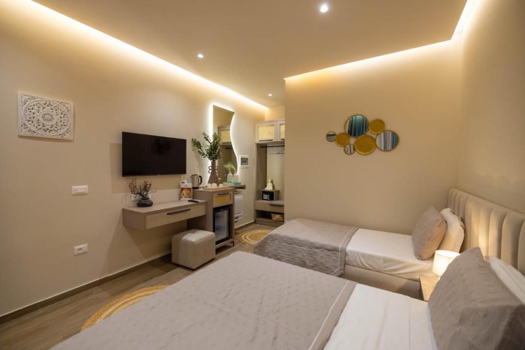 a hotel room with two beds and a television at Del Mare Rooms in Vlorë