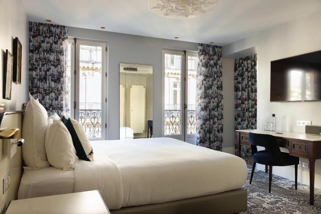 une chambre avec un grand lit et un bureau et un bureau dans l'établissement Normandy Le Chantier, à Paris