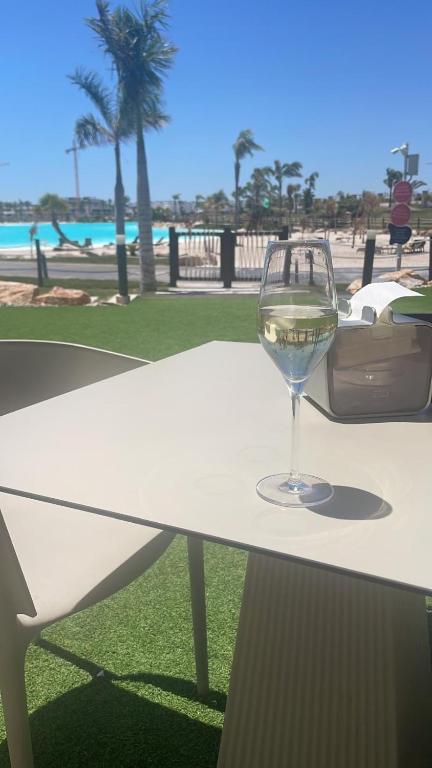 a glass of wine sitting on a table near the beach at Santa Rosalia Lake & Life resort in Torre-Pacheco