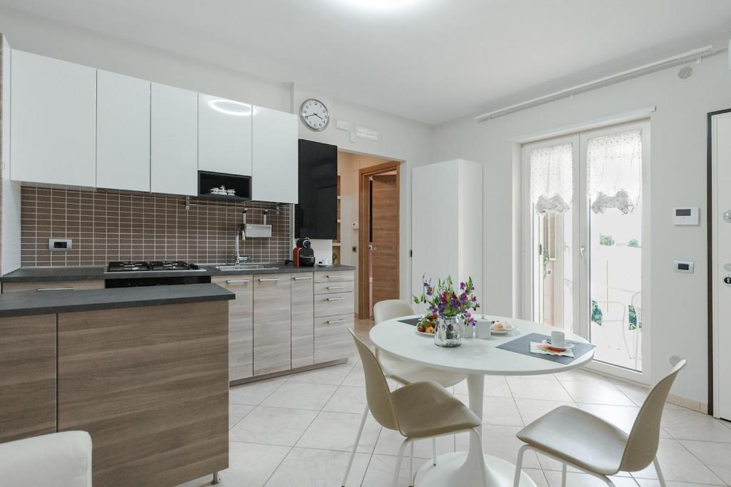 a white kitchen with a white table and chairs at Brezza di Mare Apartment in Scanzano