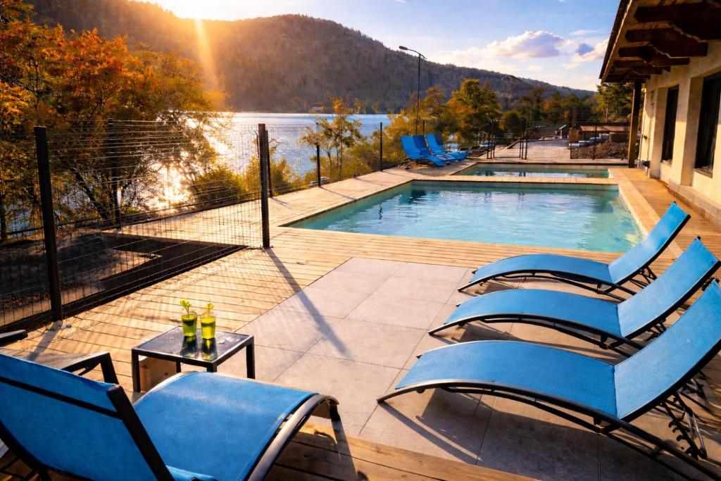 a pool with chairs and a table with a view of the water at Domusigua in Gérardmer