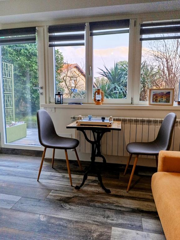 a table and two chairs in a room with windows at Altea - Lago di Como nuovo accogliente mini appartamento vicino alla spiaggia e giardino in Dervio