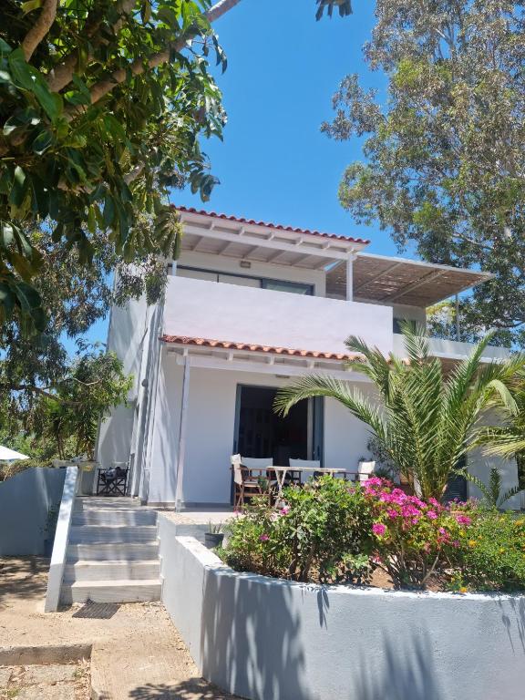 a white house with stairs and flowers at Pebble Home in Yialós