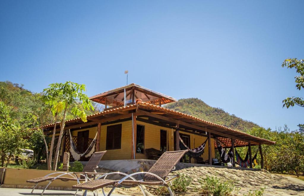 a house with chairs in front of it at Pousada Cajuzinho do Cerrado in Cavalcante