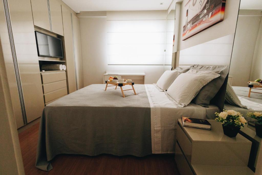 a bedroom with a bed with a table on it at LRFlat 3 - Flat para pessoas exigentes com requinte e conforto próximo de tudo! Garagem e portaria 24h in Montes Claros