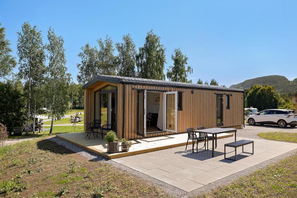 a tiny house with a patio and a table at First Camp Lunde - Telemark in Lunde