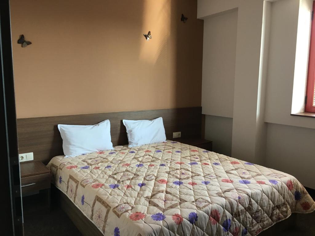 a bedroom with a bed with a comforter and two pillows at Hotel Iris in Plovdiv