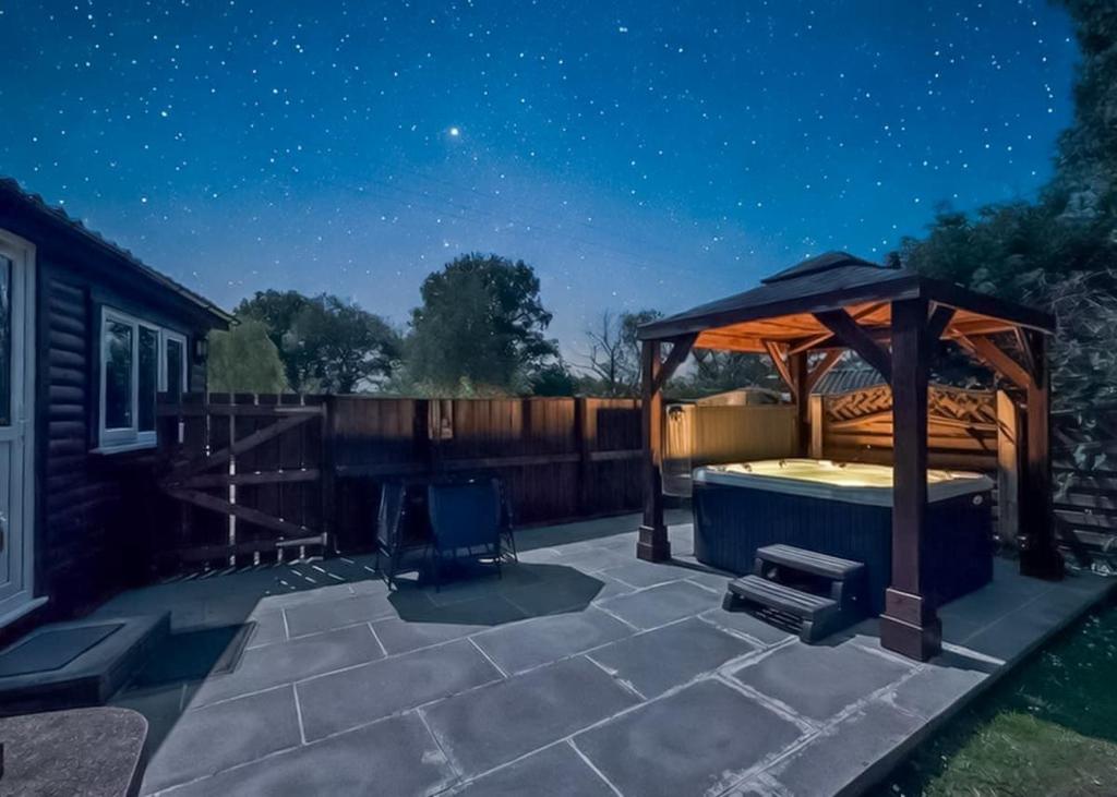 a patio at night with a gazebo at Heronstone Lodges in Ystalyfera