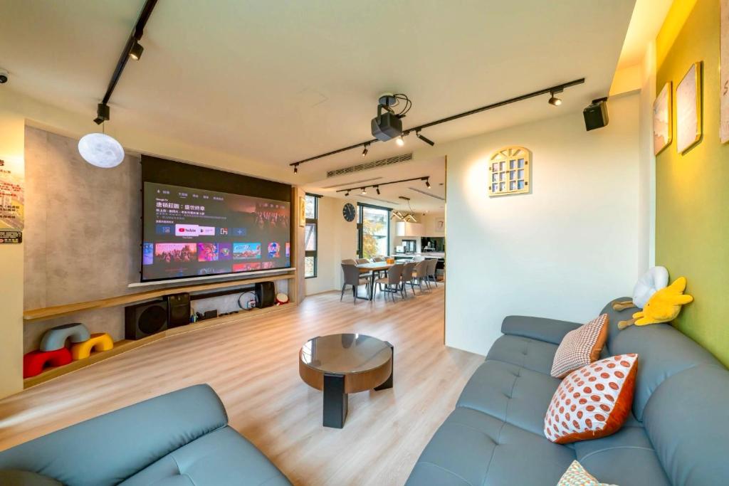 a living room with a blue couch and a flat screen tv at 閒晃趣-包棟民宿-依訂房人數提供房間數 in Ch'i-wu-lao