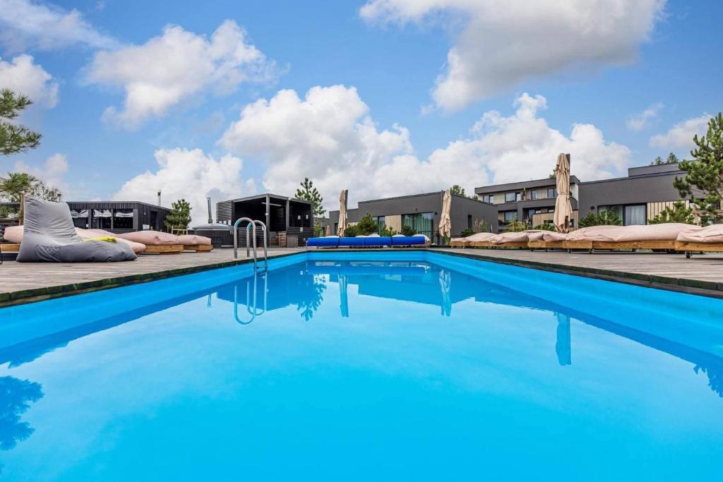 a swimming pool with blue water in front of a building at Harmony Shore Apartments in Palanga