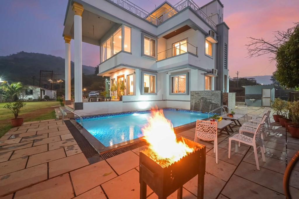 a house with a fire pit in front of a swimming pool at 6BHK White Castle Villa in Malavli