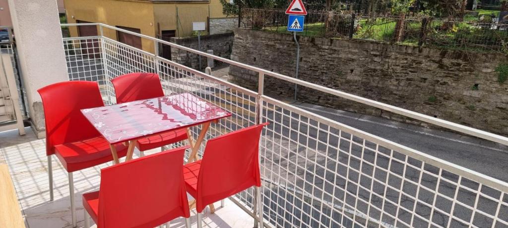 a table and red chairs on a balcony at Melis Apartment in Como