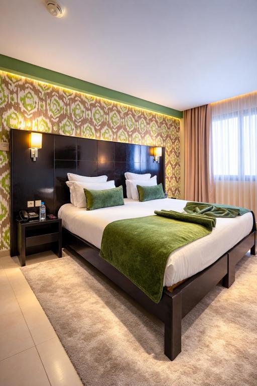 ein Schlafzimmer mit einem großen Bett und einer grünen Wand in der Unterkunft Hôtel du Golf Mohammedia in Mohammedia