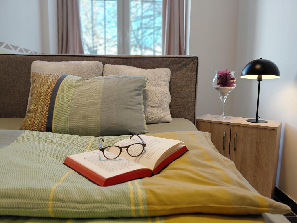 a book and pair of glasses sitting on a bed at Ferienwohnung CityImmo in Gotha