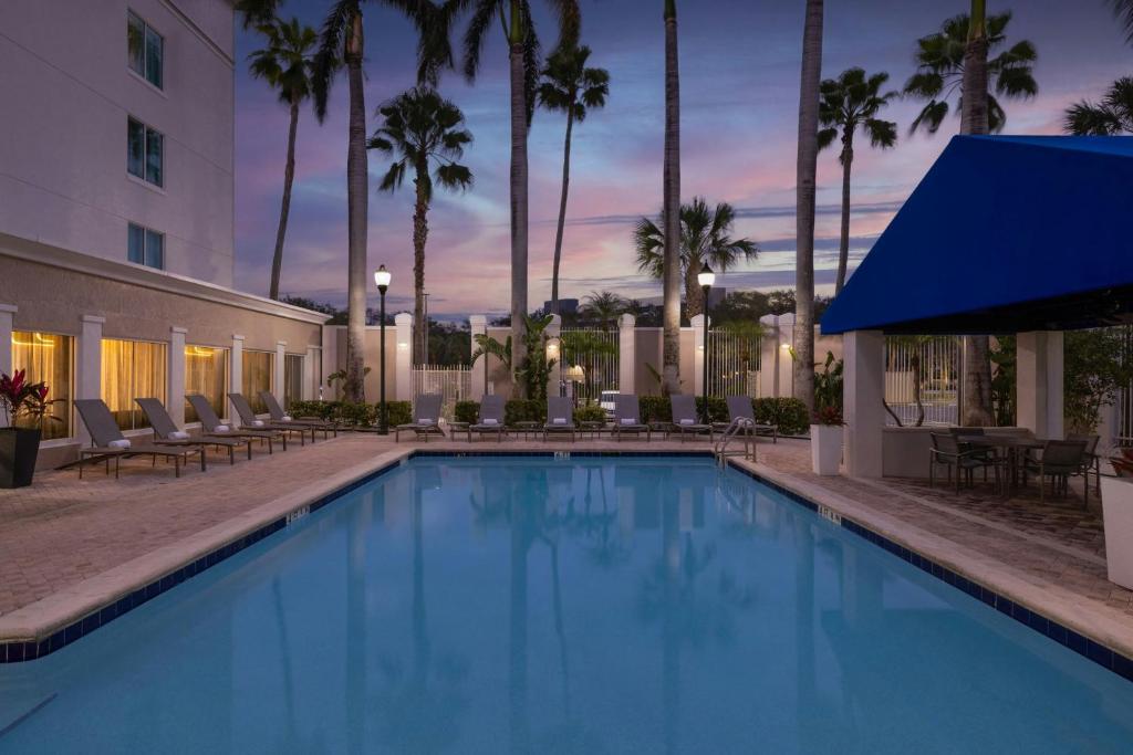 a large swimming pool with chairs and a building at SpringHill Suites Boca Raton in Boca Raton