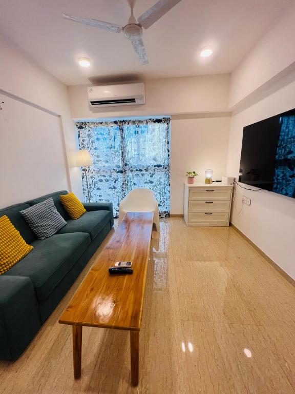 a living room with a green couch and a wooden coffee table at Serene white studio - 2nd floor in Dehu Road