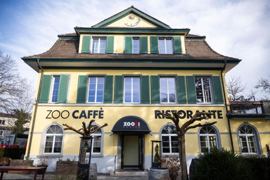 a yellow and green building with a clock on top at B&B Zoo Caffè & Ristorante in Zurich