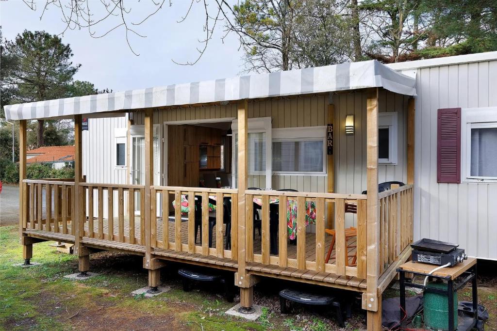 a small house with a porch and a deck at Mobile Home du Bois Dormant in Saint-Jean-de-Monts
