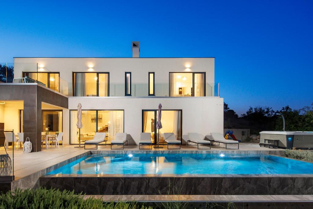 a house with a swimming pool in front of it at Villa Aristea with sea view, jacuzzi and infinity pool in Vicani