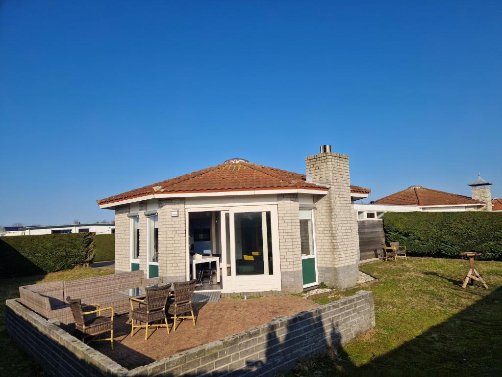 a small house with chairs and a porch at De Golfakker in Hollum