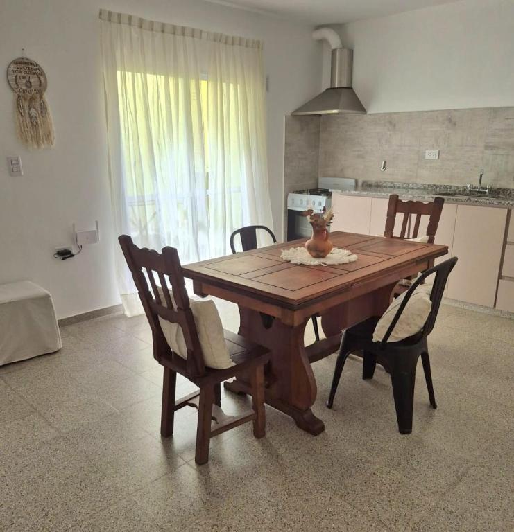 a dining room table with chairs and a kitchen at CasaMora departamento céntrico con cochera gratis, 2 habitaciones in Almafuerte
