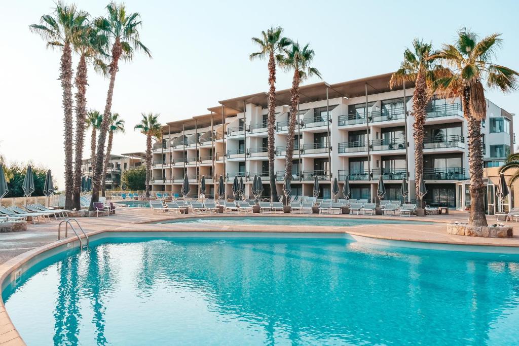 a hotel with a swimming pool and palm trees at Thalazur Antibes - Hôtel & Spa in Antibes