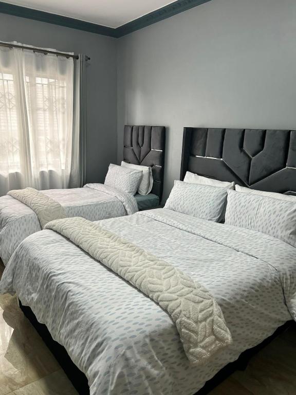 a bedroom with two beds with white sheets and a window at Crompton Gardens 786 in Durban