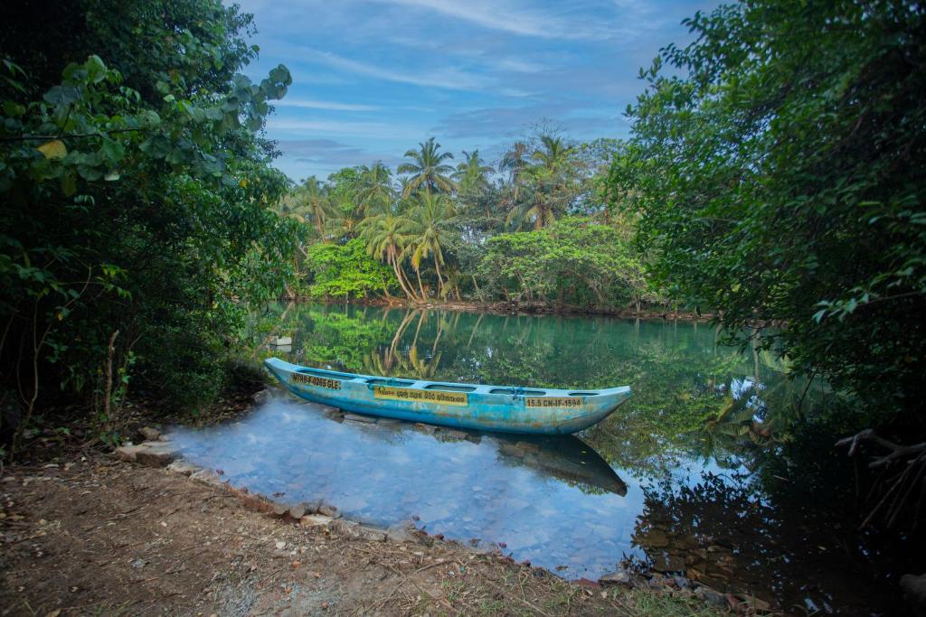 a blue boat sitting in the water on a river at Serene Vista Villa, formerly Bungalows in Hikkaduwa
