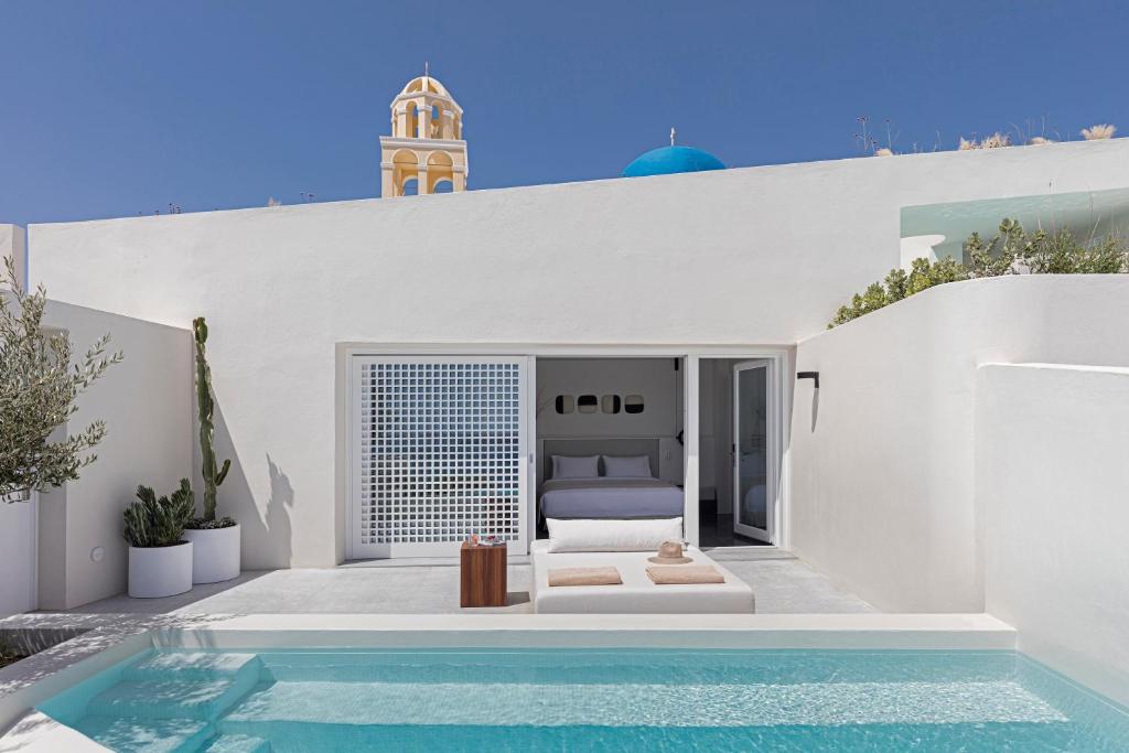 a bedroom with a bed and a swimming pool at Canaves Oia Suites - Small Luxury Hotels of the World in Oia