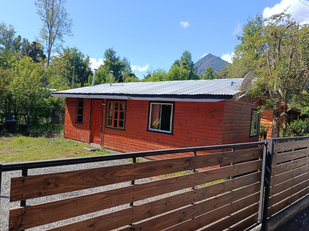 a red house with a fence in front of it at cabaña vale in Coñaripe