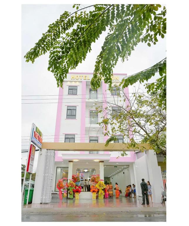 a pink building with people standing outside of it at Hotel Tri Tôn in Tri Tôn