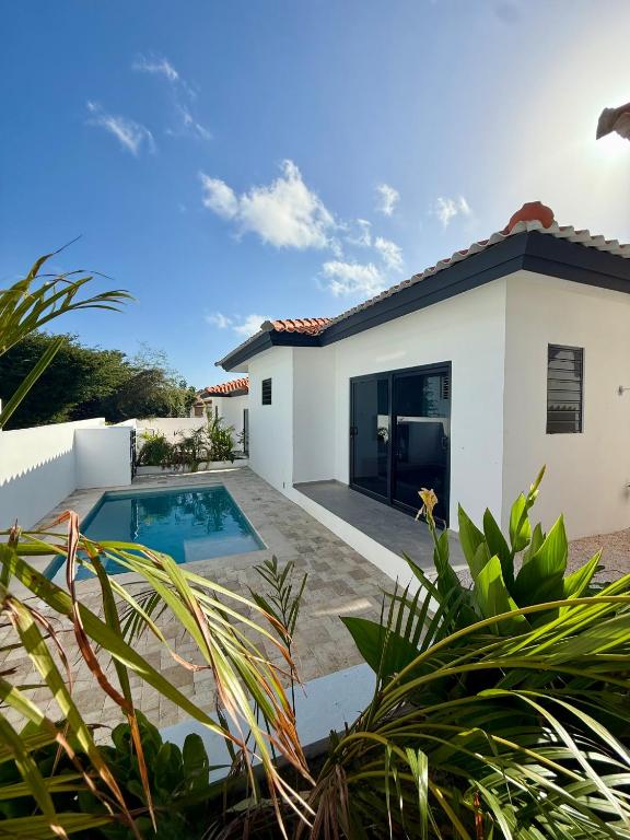 a white house with a swimming pool and plants at Tropilena Resort in Willemstad