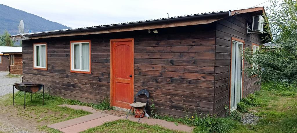 a small wooden cabin with a red door at cabaña zoila in Coñaripe