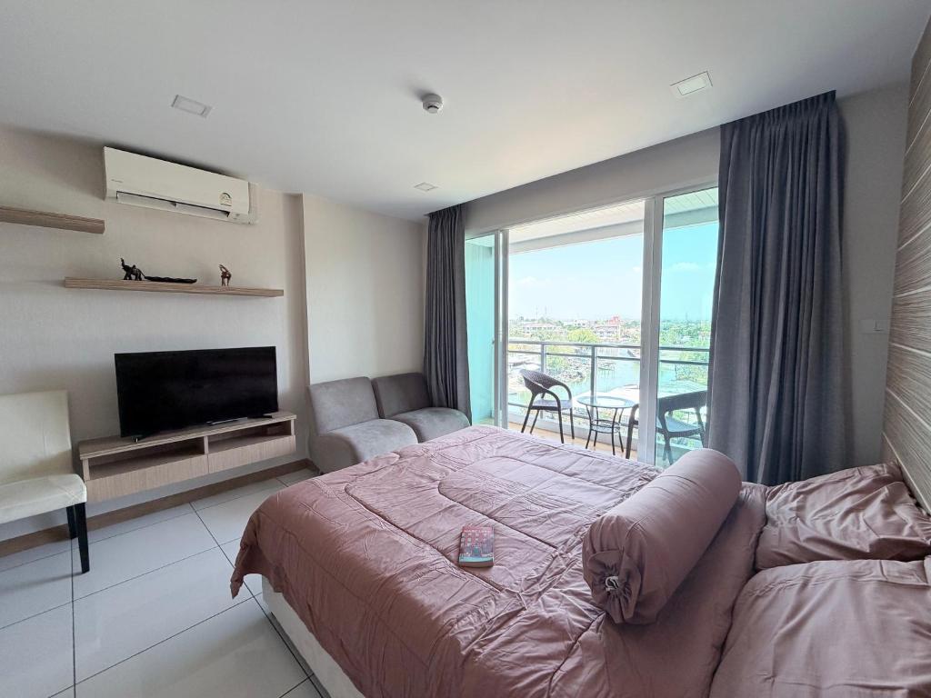 a bedroom with a bed and a television and a balcony at Whale Marina Condo in Na Jomtien