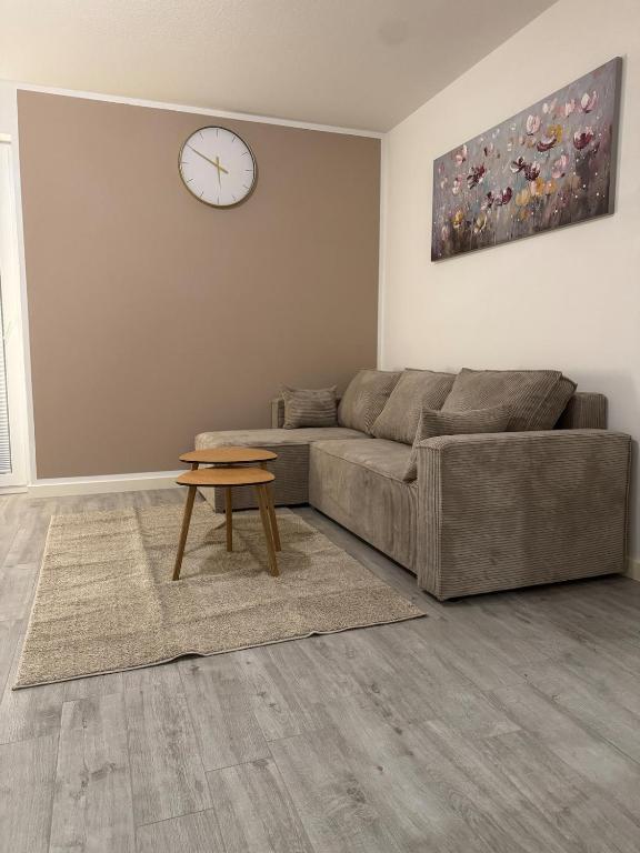 a living room with a couch and a clock on the wall at Lingen Stay in Lingen