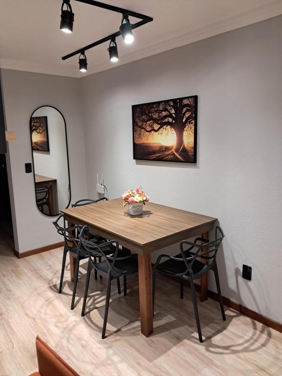 a dining room table with chairs and a painting on the wall at Apartamento completo e perfeito, Ao lado da Weg in Jaraguá do Sul